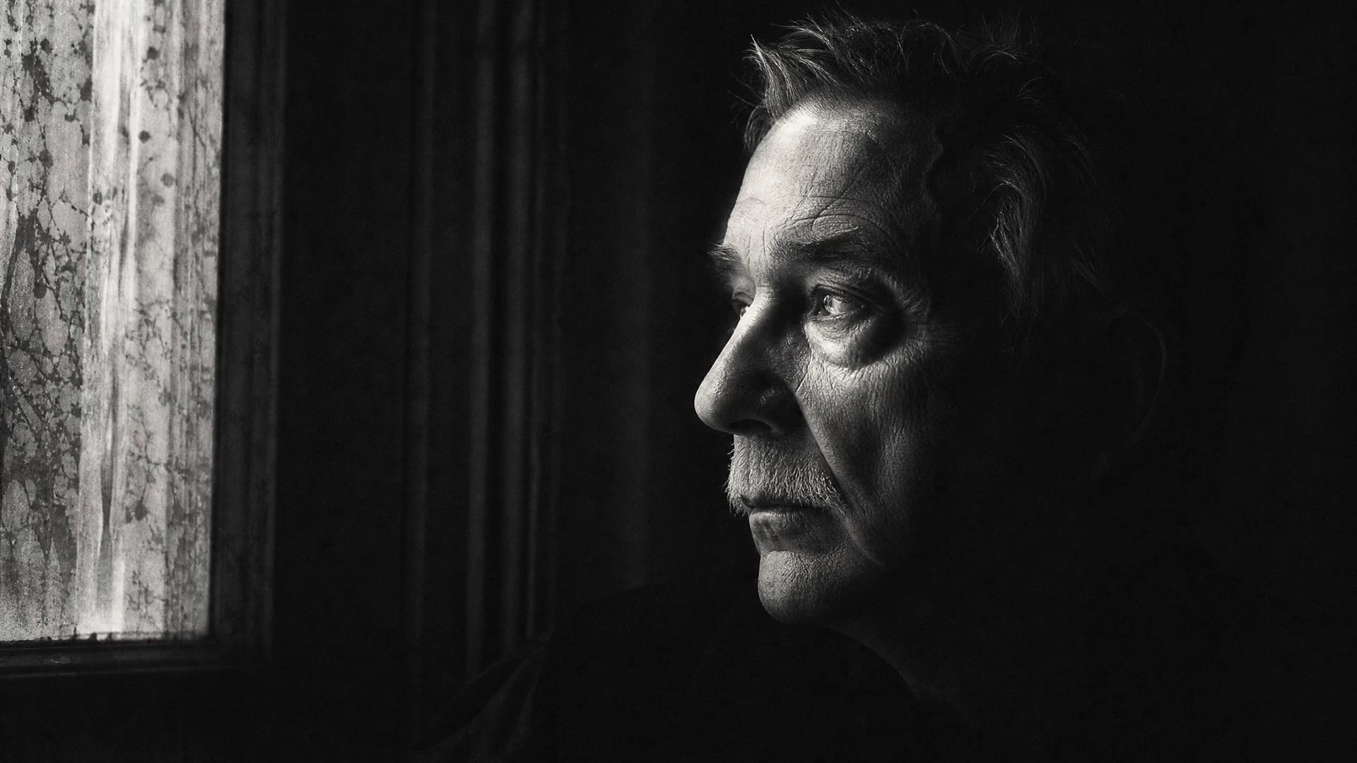 Older adult looking out a window. The invisibility of aging