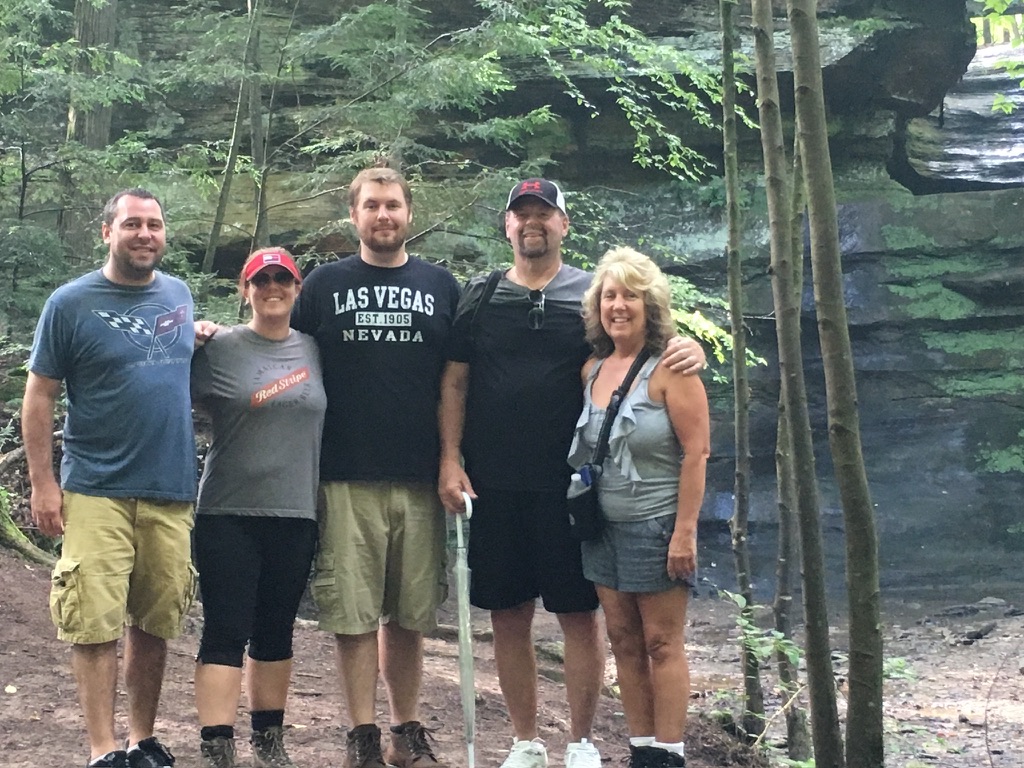 Joby Horn standing with his family on a wooded trail